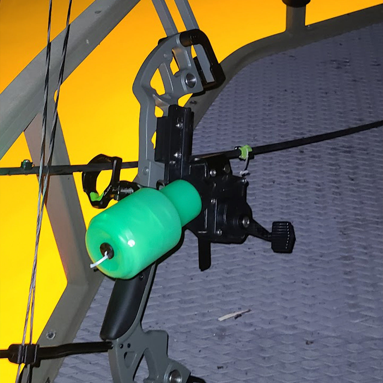 Bright green bowfishing float and reel attached to a compound bow for aquatic target shooting.