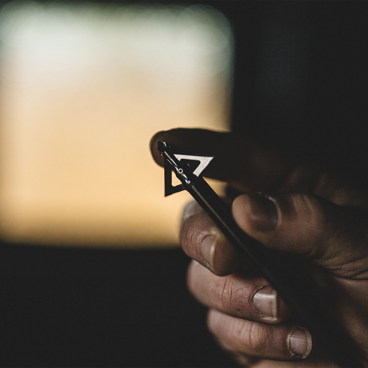 Hand adjusting a bow sight, close-up of archery gear used in bowhunting.