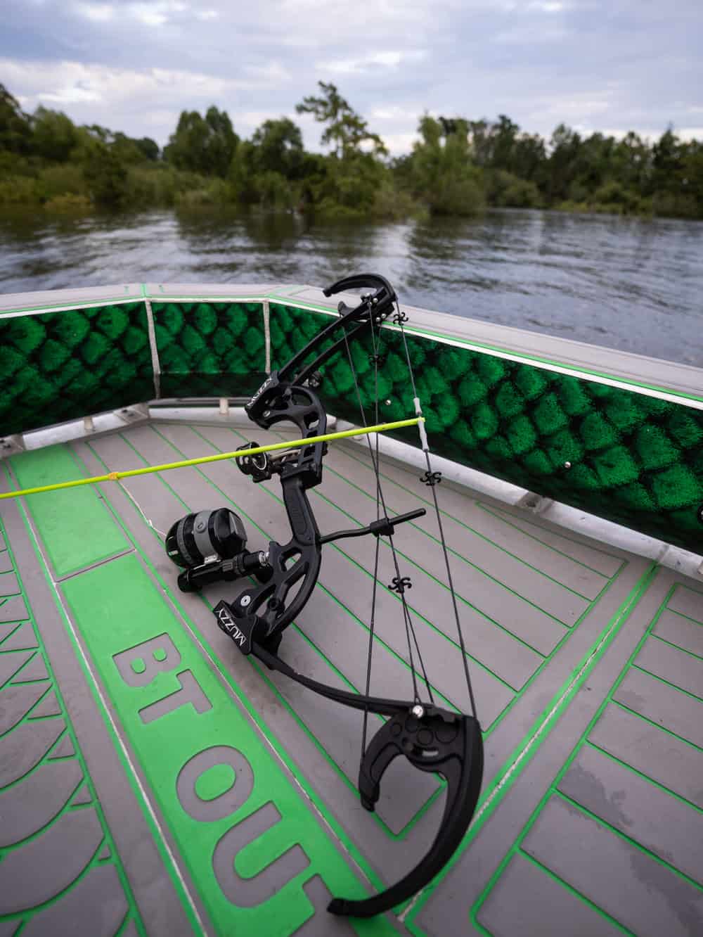 1. Compact fishing bow mounted on a boat with water and trees in the background.