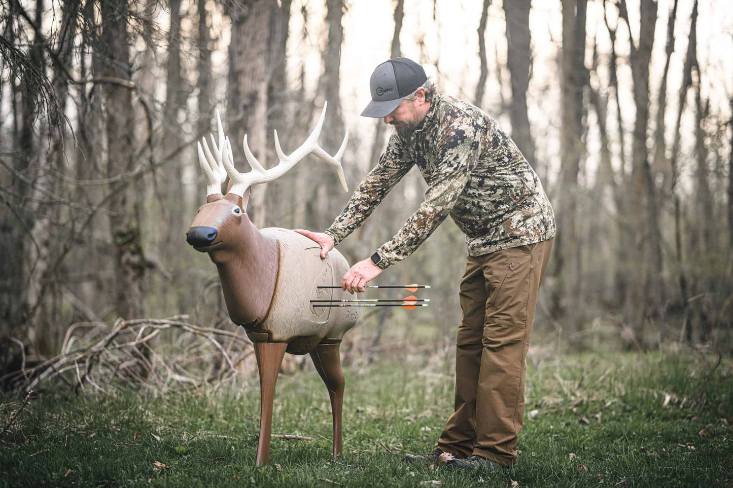 Real or simulated deer target in a wooded outdoor setting for archery practice.