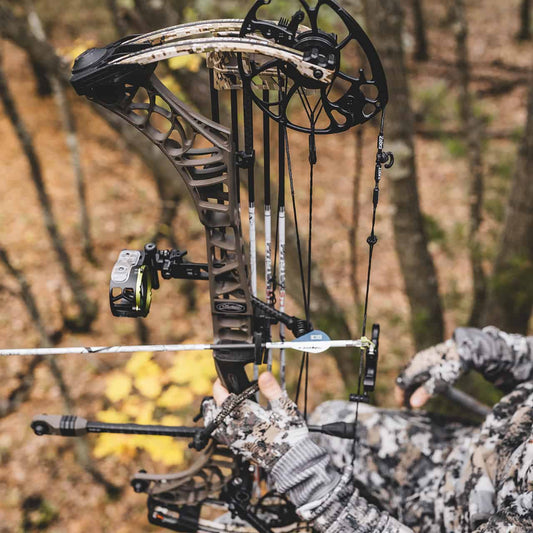 High-performance compound bow with camo grip for archery hunting in wooded terrain.