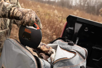 Portable hunting game call device in outdoor terrain.