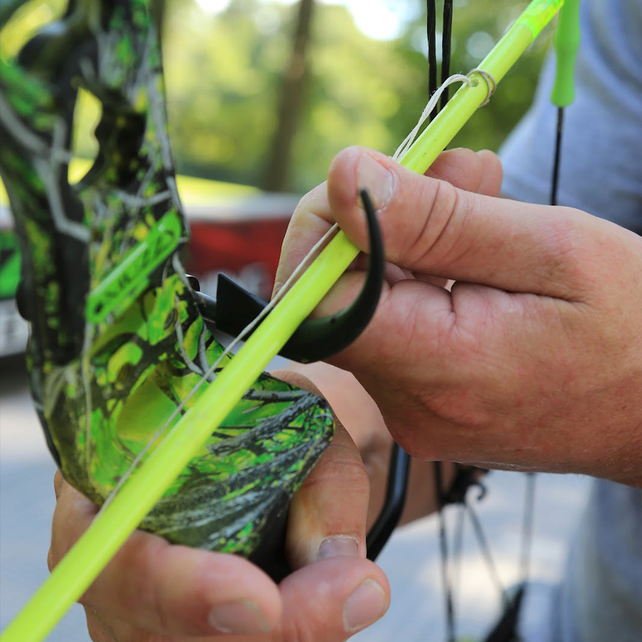 Bright green bow stabilizer attached to camo bow for archery stability and accuracy.