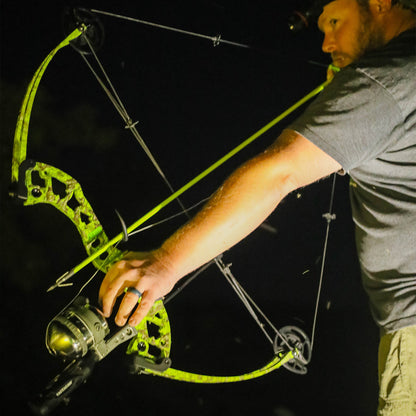 Bright green compound bow and arrow at night for bowhunting outdoors.