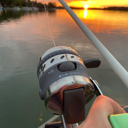 A fishing reel on a boat during a colorful sunset over calm water.