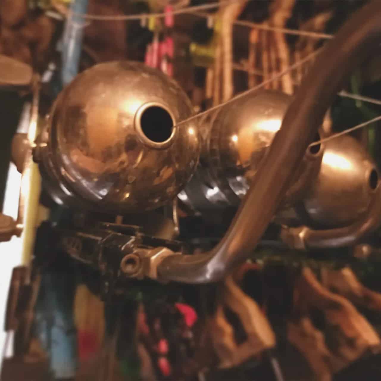 Bronze-colored artillery shells hanging on a rack in a workshop or storage area.