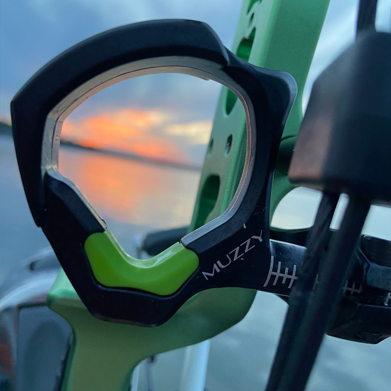 Adjustable archery sight on bow with sunset reflected on water, perfect for bowhunting.