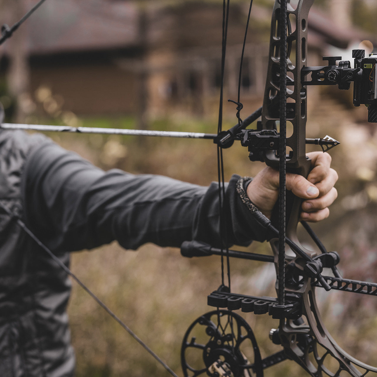 High-tech compound bow with scope, held by archery enthusiast during outdoor hunting session.