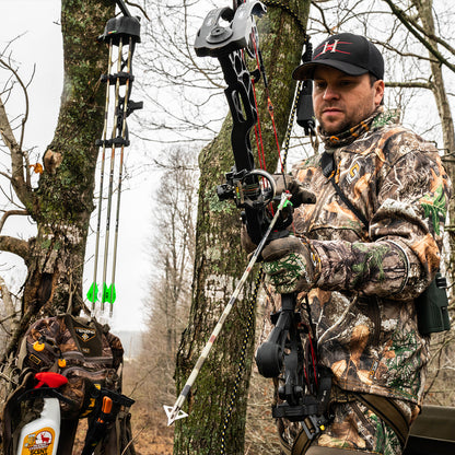 Camouflage bow hunting gear and archery equipment in forest setting for outdoor sports.