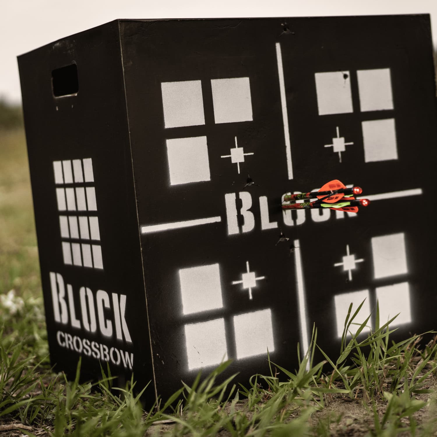 Target practice on black crossbow target with arrows hitting the bullseye outdoors.