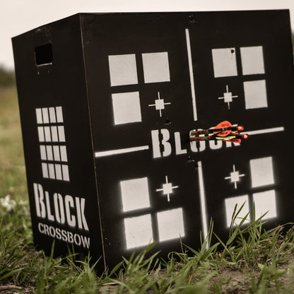 Target practice on black crossbow target with arrows hitting the bullseye outdoors.