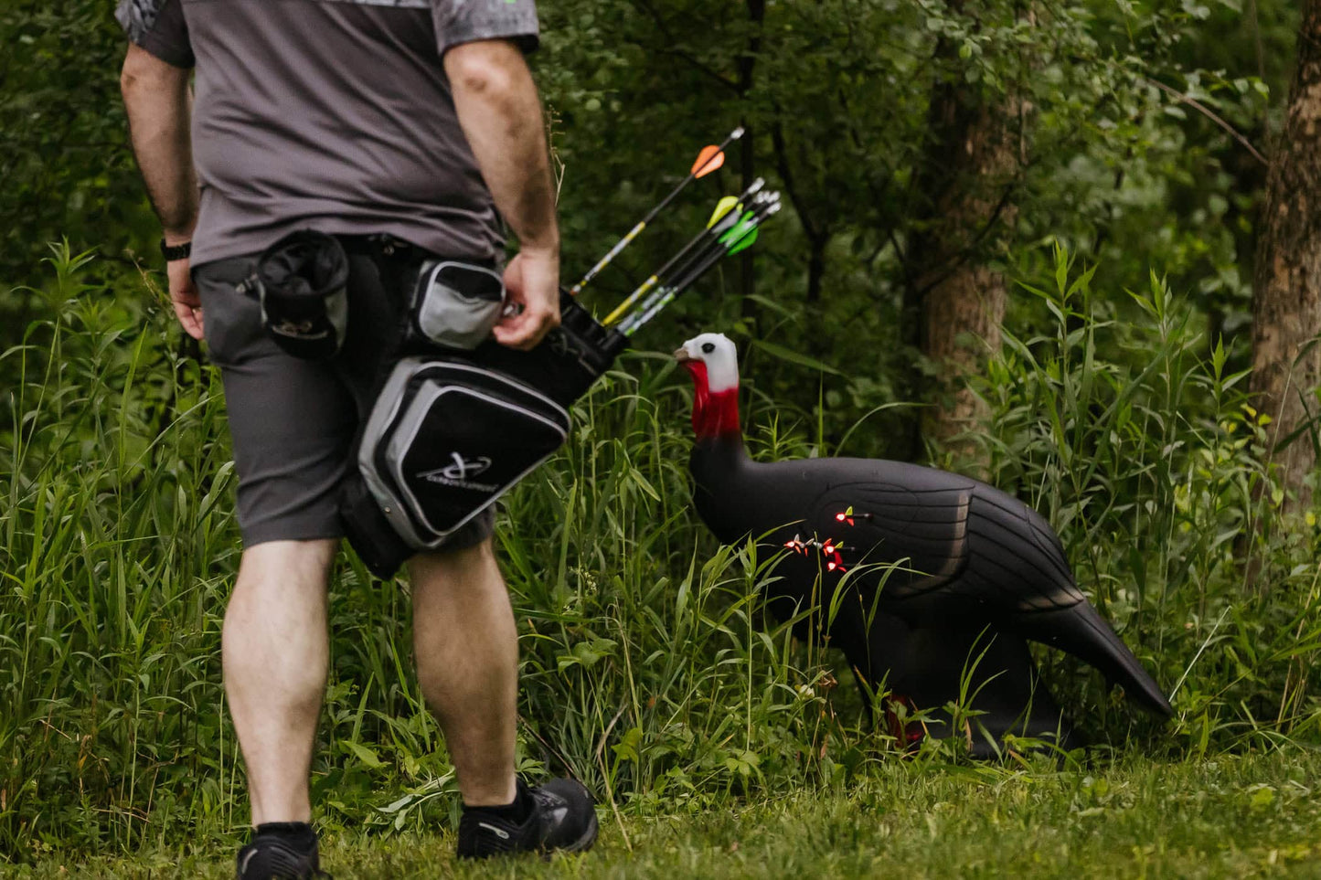 Archery target in wooded outdoor setting with hunter preparing to shoot.
