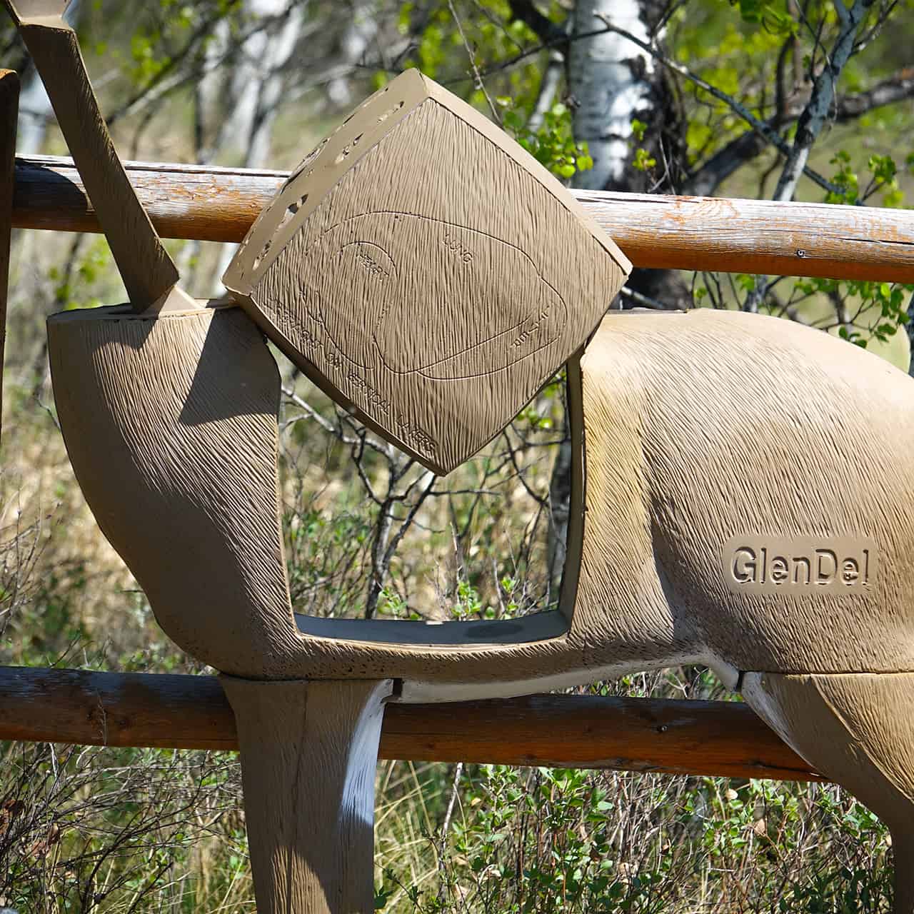 Camouflage ground blind with deer silhouette and arrow for bowhunting, set against natural outdoor foliage.