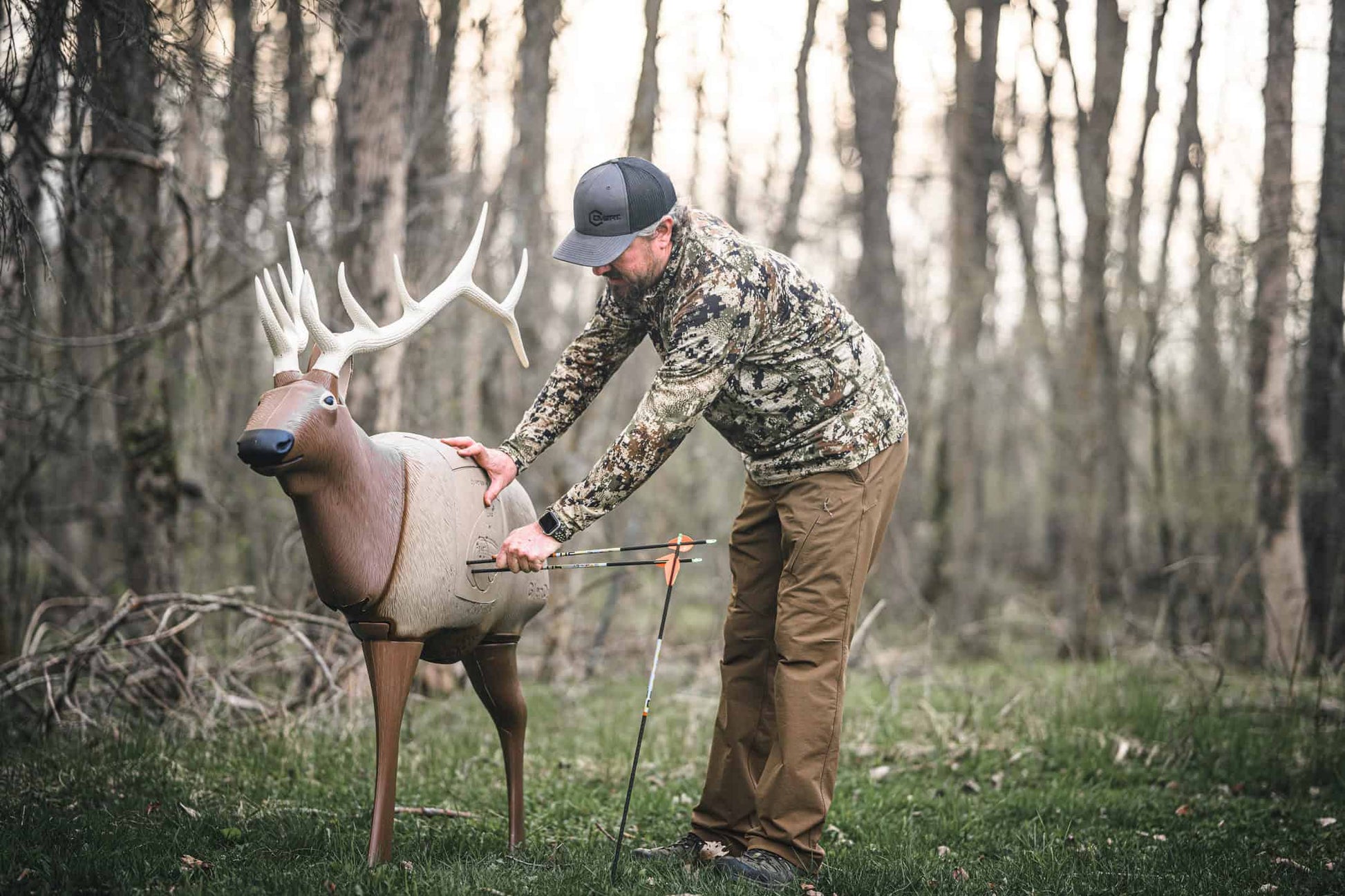 Realistic deer target on outdoor archery range with man practicing shooting at dusk.