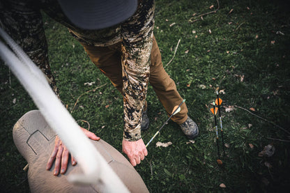Archer’s setup in a ground blind with arrows on the ground, preparing for bowhunting.