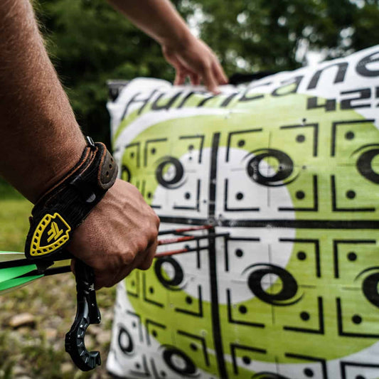 Precision archery target practice with a close-up of a bow and arrow shot at a vibrant, multi-patterned target outdoors.