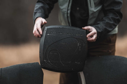 1. Mounting a black archery draw weight scale on a wooden stand, indoors in a archery range.