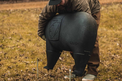 Black deer feeder with the brand name "dlenfel" on it, set up outdoors on grassy terrain.