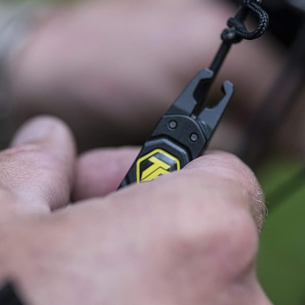 Black archery release aid with yellow logo being operated outdoors.