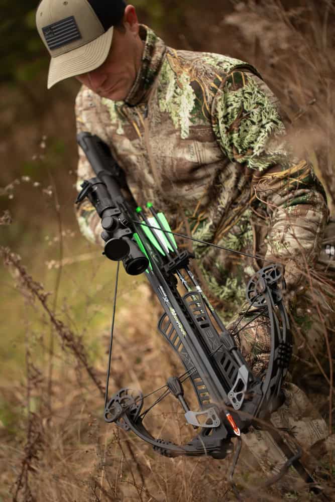 High-tech crossbow with illuminated scope in natural outdoor setting for hunting.