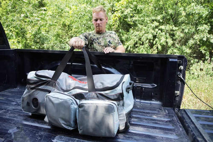 Heavy-duty hunting gear bag in truck bed, outdoors setting, preparation for bowhunting trip.