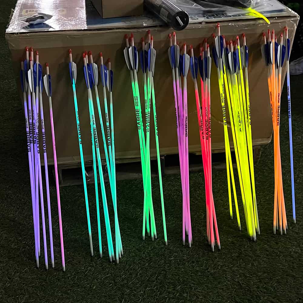 Glow-in-the-dark archery arrows with bright neon colors and fletching, ideal for night bowhunting and outdoor archery activities.