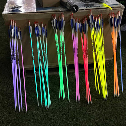Glow-in-the-dark archery arrows with bright neon colors and fletching, ideal for night bowhunting and outdoor archery activities.
