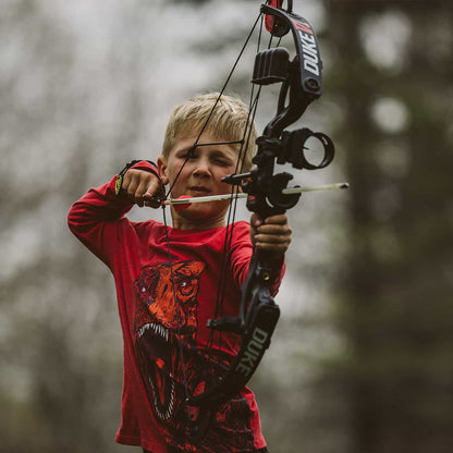 Precision child archery shooting with a tactical bow outdoors at dusk, emphasizing safety and focus.