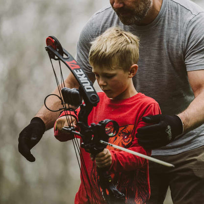 Protective archery arm guard on young boy during outdoor bowhunting activity.