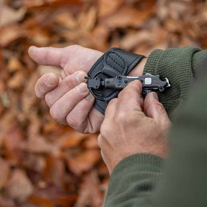 Compact tactical knife attached to wrist strap for outdoor survival or hunting tasks.