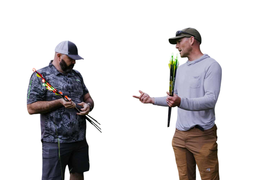 Bright outdoor scene of two men preparing for bowhunting with a deer target and arrows in a forest setting.