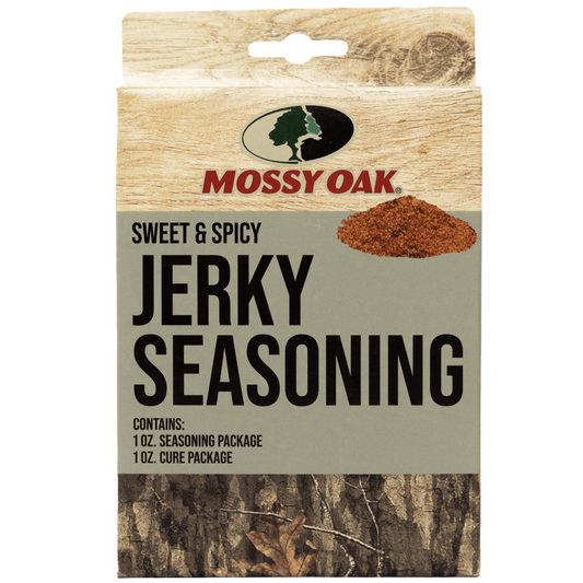 Bold text in the image: "Mossy Oak Sweet & Spicy Jerky Seasoning Mix" with a background of wood and forest floor.