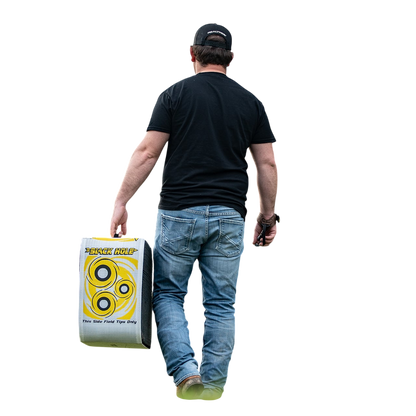 Target practice with archery training target at outdoor field, man carrying shooting supplies, focus on archery equipment.