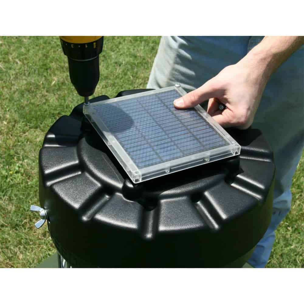 Small solar panel with a grid pattern resting on a black outdoor equipment container.