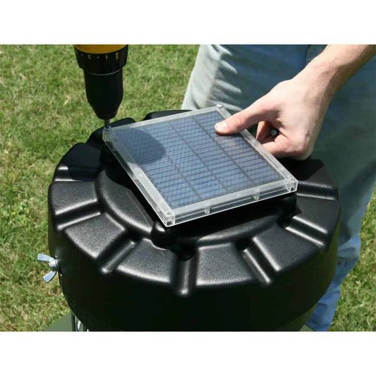 Small solar panel with a grid pattern resting on a black outdoor equipment container.